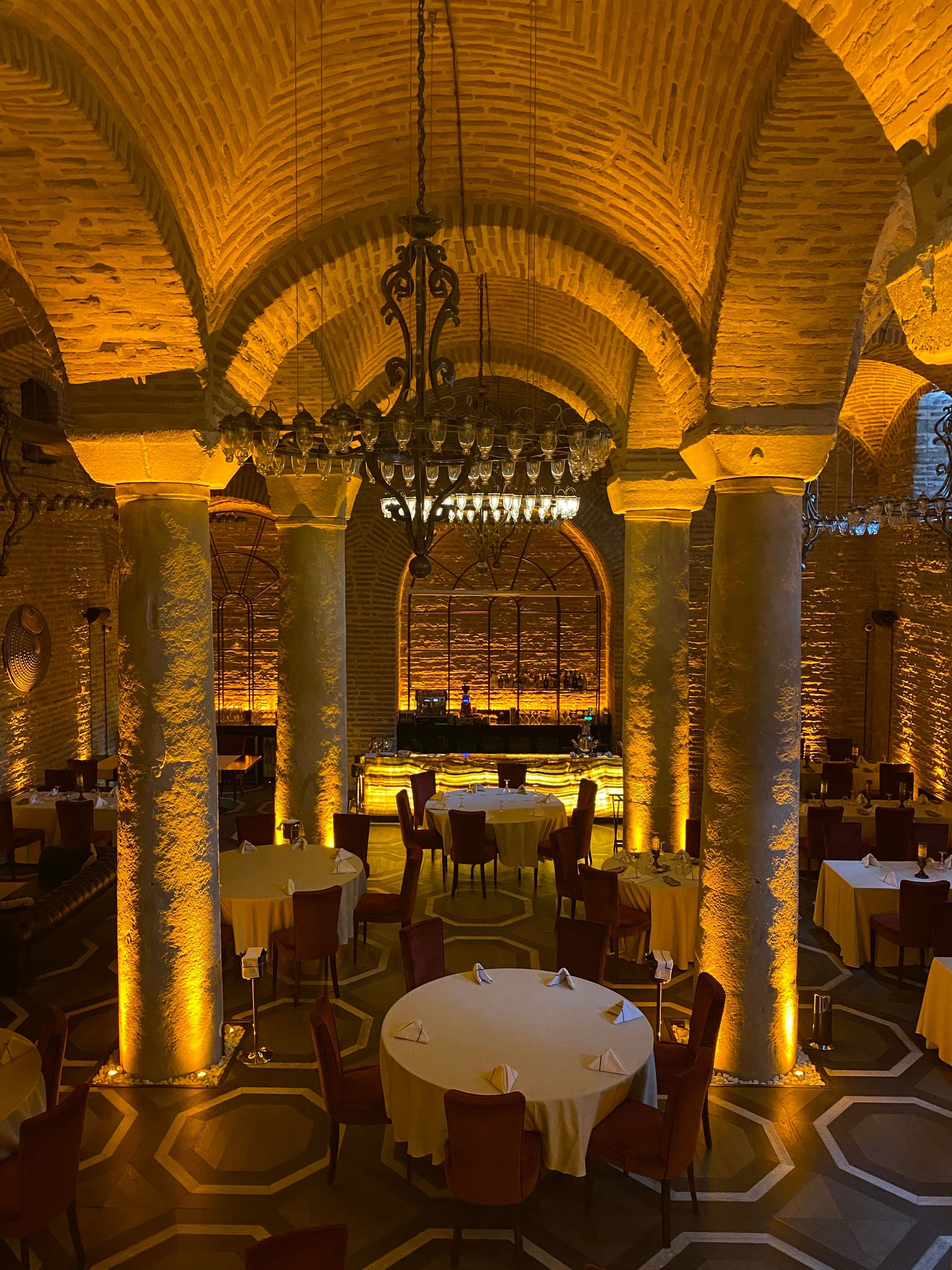 Comedor en penumbra con velas sobre manteles de lino